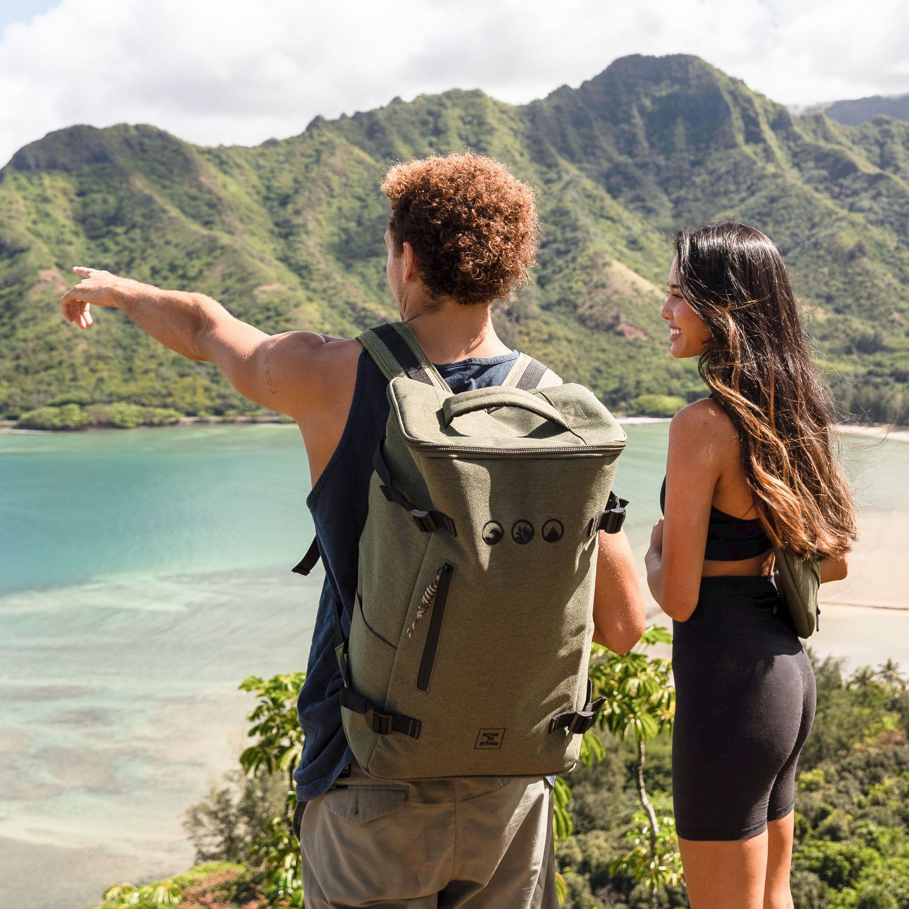 Moodige Bild Outdoor Mann traegt den Toploader Rucksack KOLOA in olive-gruen auf dem Rücken und schaut aufs Meer