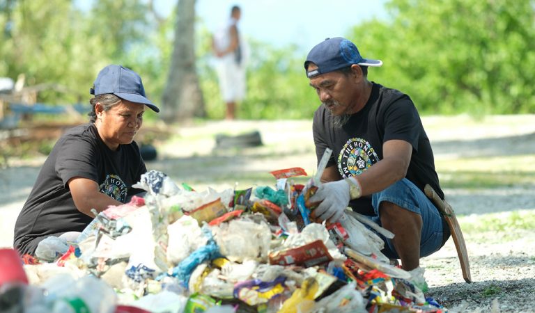 Picture of a woman and a man sorting the ocean plastic on the beach