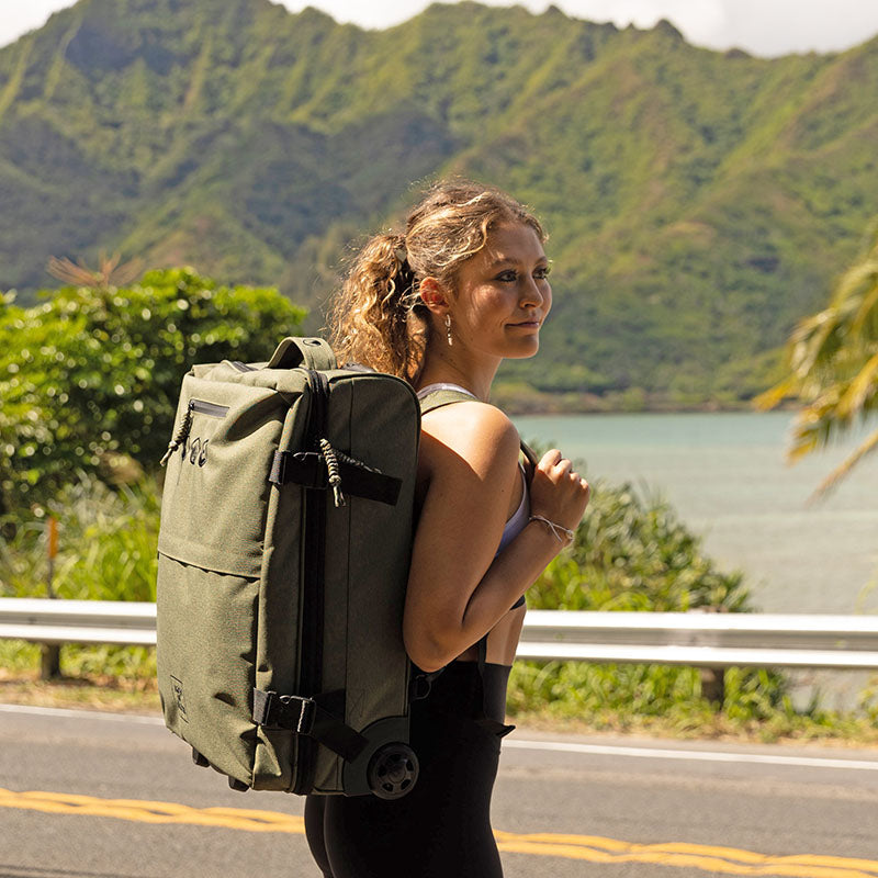SONS OF ALOHA Hybrid 2in1 Rucksack Trolley Outdoor Frau traegt den Rucksack und steht am Meer