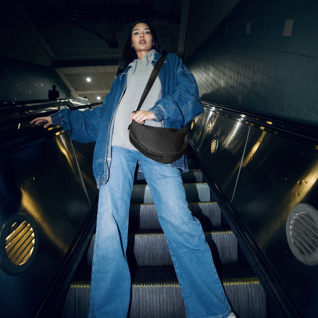 Moodbild Moon Bag HOKU schwarz (m)Frau steht auf der Rolltreppe von einer U-Bahnstation und fährt hoch