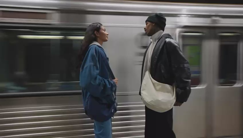 Load video: Werbevideo Moon Bag M und XL Mann und Frau stehen an einer U-Bahnstation und die U-Bahn fährt vorbei