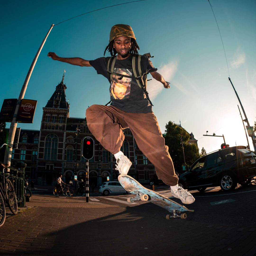 SONS OF ALOHA Rolltop Rucksack KANE olive - grün Moodbild Mann traegt Skaterkleidung und springt mit einem Skateboard in der Luft.