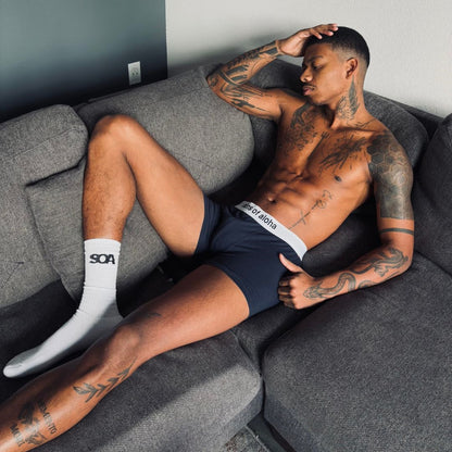 SONS OF ALOHA Boxershorts blau mit weißem Bund Mann posiert auf einem Sofa