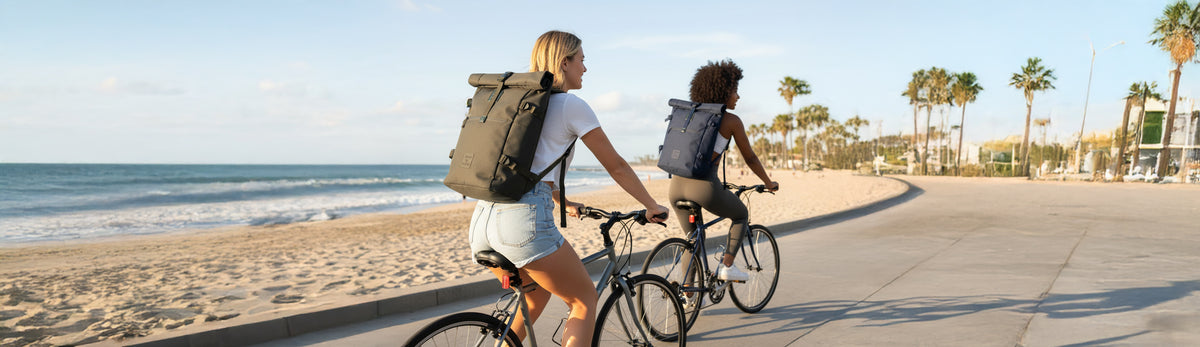 zwei Frauen in Los Angeles auf dem Fahrrad mit grünem und blauen Rolltop Rucksack
