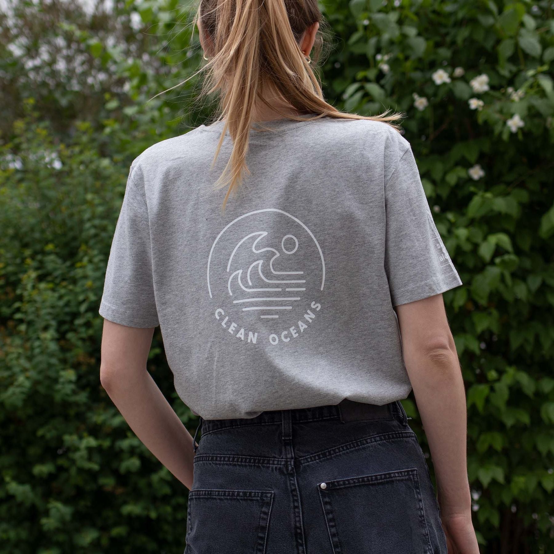 Bio Baumwolle T-Shirt in grau Outdoor Frau traegt t-Shirt Rückendruck "Clean Ocians" 
